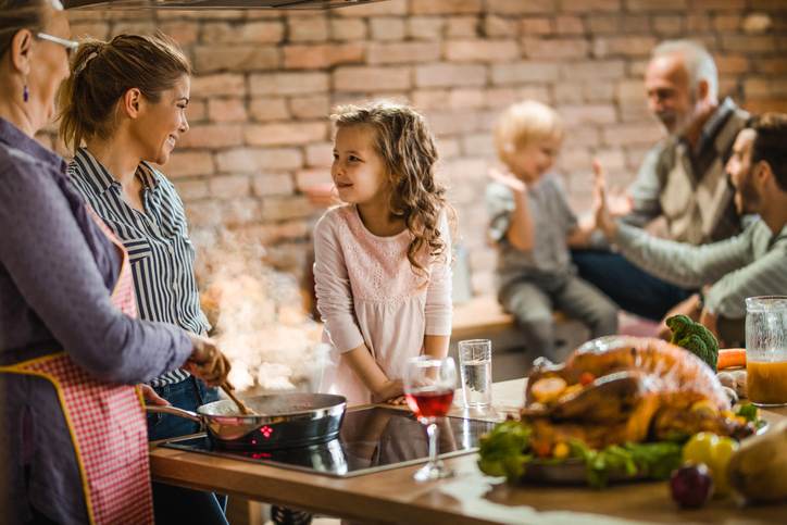 Happy female members of extended family talking while preparing a dish for Thanksgiving.