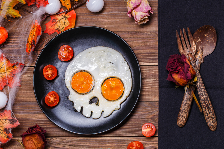 Fried eggs in the shape of a skull and fresh tomatoes. Breakfast in Halloween decorations.