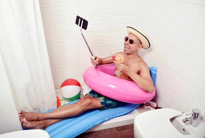 man with swim ring taking selfie in the bathroom